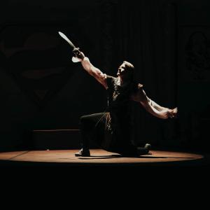 An M State actor holds a sword into the spotlight on the Waage 剧院 stage